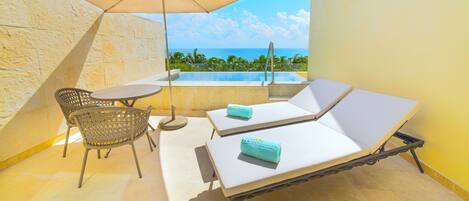 Un balcon avec une piscine, deux chaises longues, une table et une chaise.
