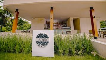 An outdoor seating area with a modern design, featuring a large circular sign with the text "ES NIU" and a geometric pattern.