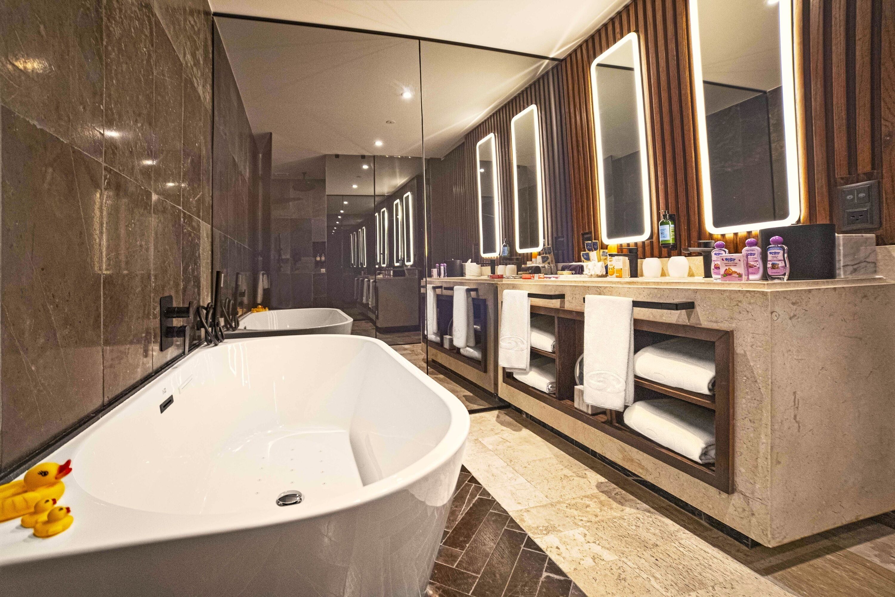 A modern bathroom with a freestanding bathtub, multiple mirrors, and a vanity with towels.