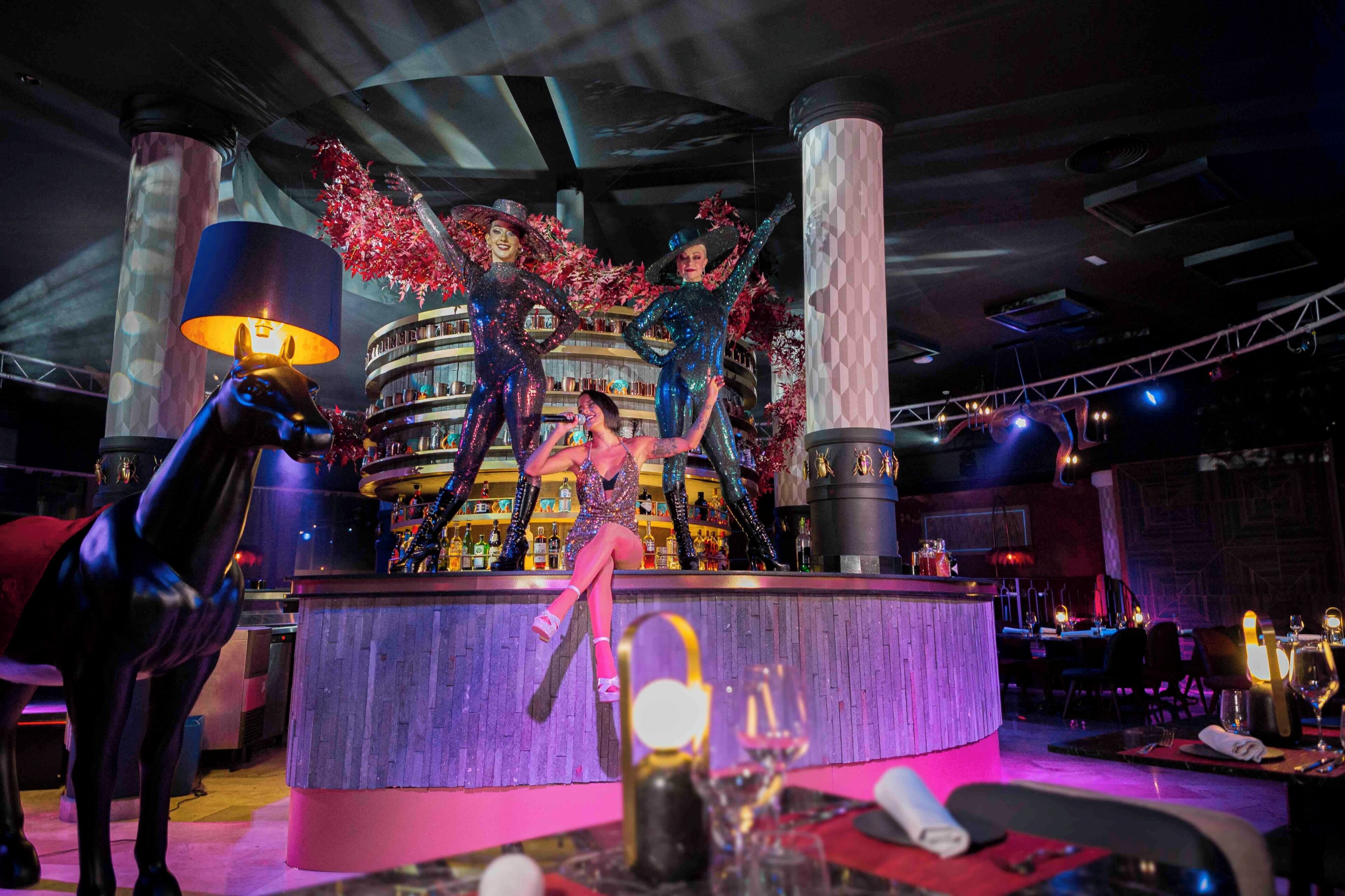 A bar area with a circular bar counter, stools, and a decorative backdrop.