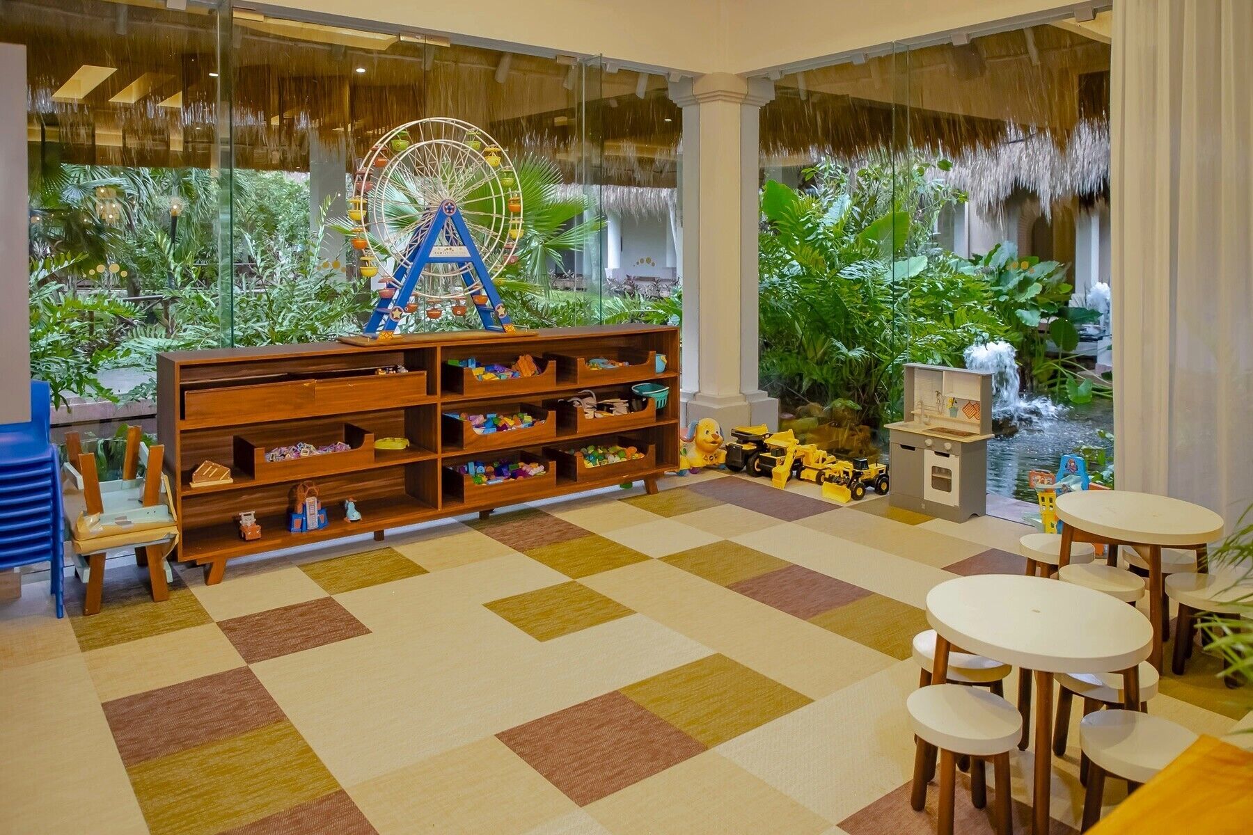 Un área de juegos infantiles con una gran estantería de madera, una noria y una pequeña cascada interior.