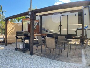Enjoy dining and socializing in the covered living area of this RV, complete with a grill for outdoor cooking.
