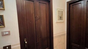 A hallway with two wooden doors, a framed picture on the wall, and a light fixture above.