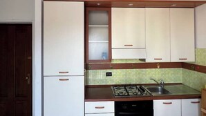 A compact kitchen with white cabinets, a gas stove, and a sink.