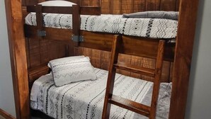 A bunk bed with a ladder, wooden headboard, and patterned bedding. - Brightstone Lake Cabin 1 (Union Township)