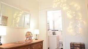 A room with a wooden dresser, a mirror, and string lights on the wall. - 6647 2W | Enchanting Studio in St. Louis (St. Louis)