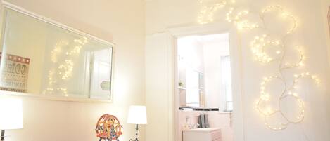 Una habitación con un aparador de madera, un espejo y luces de cuerda en la pared.