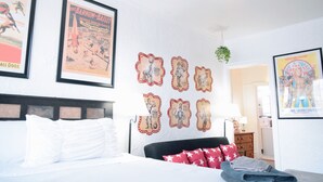 A hotel room with a bed, a headboard, a wall with framed posters, and a door leading to another room. - 6647 2W | Enchanting Studio in St. Louis (St. Louis)