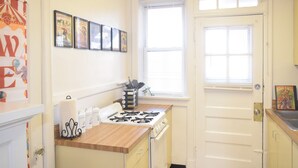 A kitchen with a gas stove, wooden countertop, and a window with blinds. - 6647 2W | Enchanting Studio in St. Louis (St. Louis)