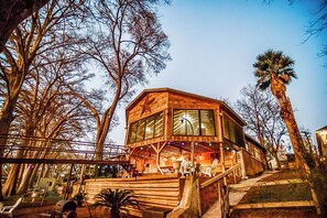 Una cabaña de madera con ventanas amplias, una terraza y una escalera que conduce a la entrada.