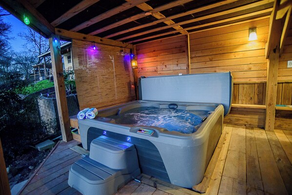 Un jacuzzi con cubierta de madera, un área techada con mosquitero y una pared de madera.