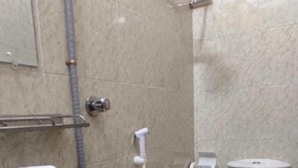 Une salle de bain avec un lavabo, des toilettes et une douche, le tout de couleur blanche.