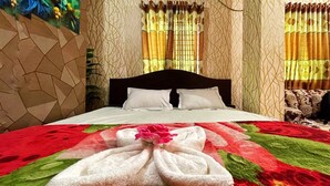 Un lit bien fait, avec des oreillers blancs et une couvre-lit à motifs rouges et verts.