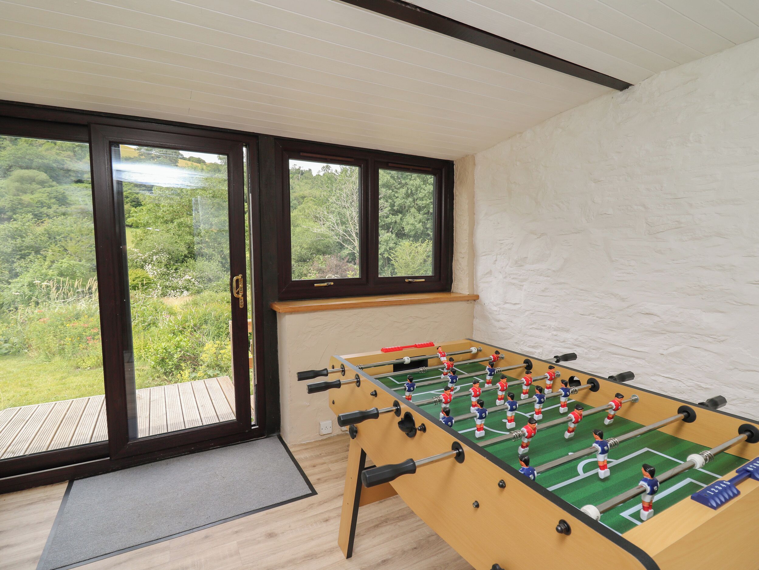 A foosball table in a room with large windows overlooking a green landscape.