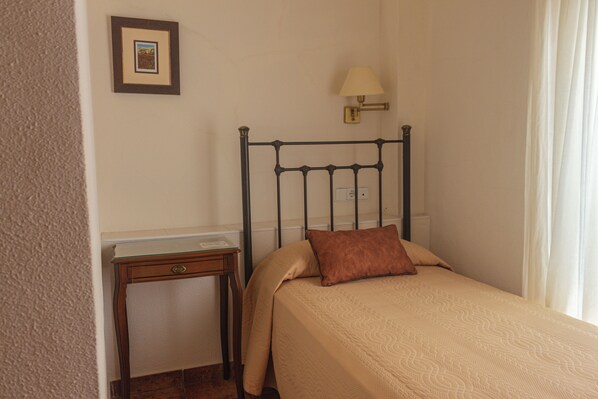 Un dormitorio con una cama, una mesita de noche, una lámpara y un cuadro en la pared.