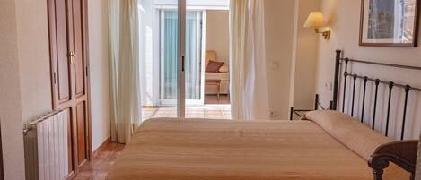 Une chambre d’hôtel avec un grand lit, un radiateur, une porte et une vue sur l’extérieur.