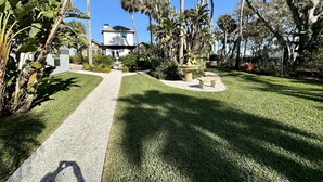 A well-maintained garden with a central pathway leading to a house. - Otium Villa - Waterfront, intercoastal villa with a Spa-like feel. (Port Orange)