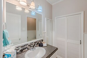 A bathroom with a white sink, a mirror, and a towel rack. There are two doors visible in the background.