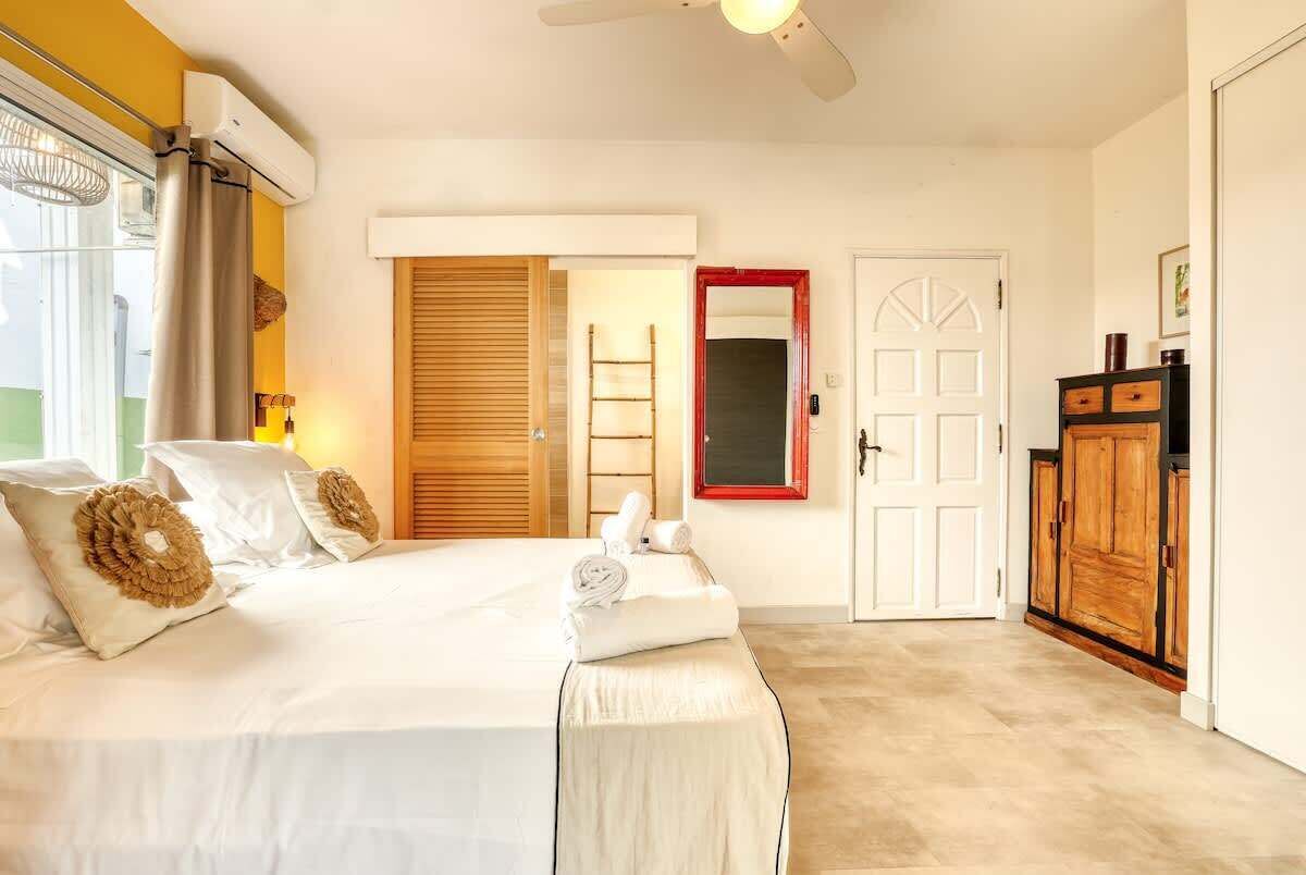 Un dormitorio con cama, armario, espejo y puerta.