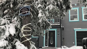 Una casa con un letrero que indica 'Suite Parking Only' y un árbol cubierto de nieve al frente.