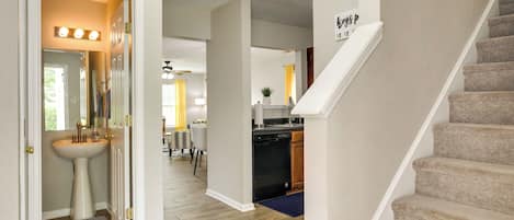 Un interior de vivienda con escalera, cocina y baño.