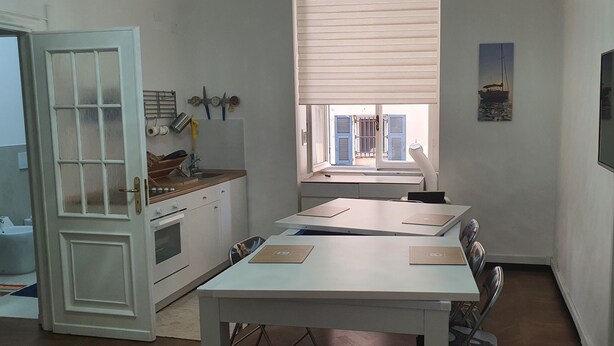 Une cuisine compacte avec une fenêtre, un coin repas avec des tables et un téléviseur fixé au mur.