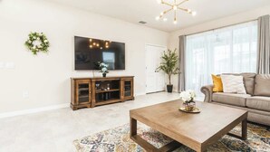 Een moderne woonkamer met een flatscreen televisie, een houten tv-meubel, een bank en een salontafel.