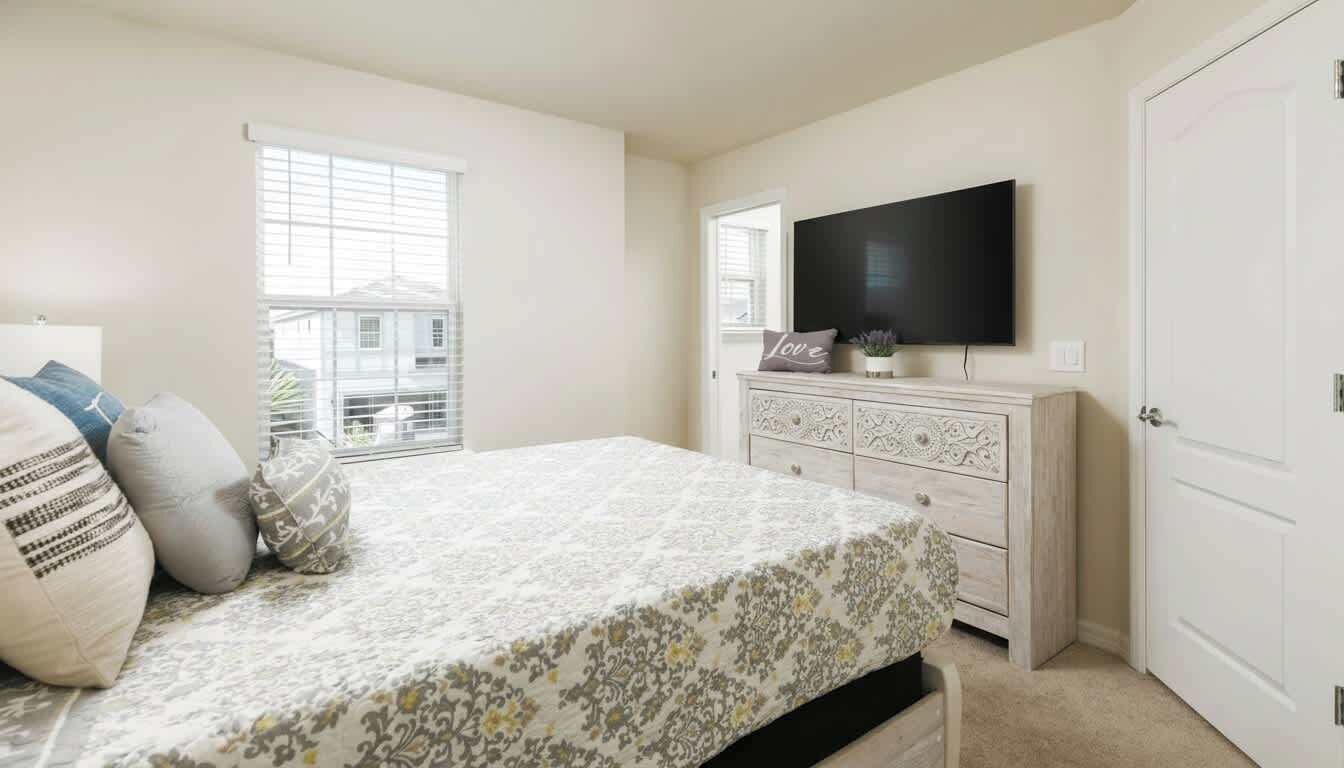 A bedroom with a bed, a dresser, a television, and a window.