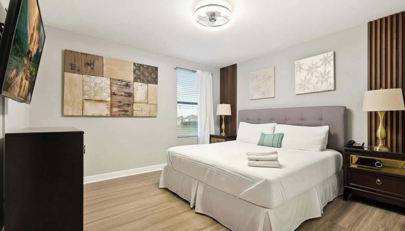 Habitación de hotel con una cama grande, un televisor de pantalla plana, una mesita de noche con lámpara y obras de arte en las paredes.