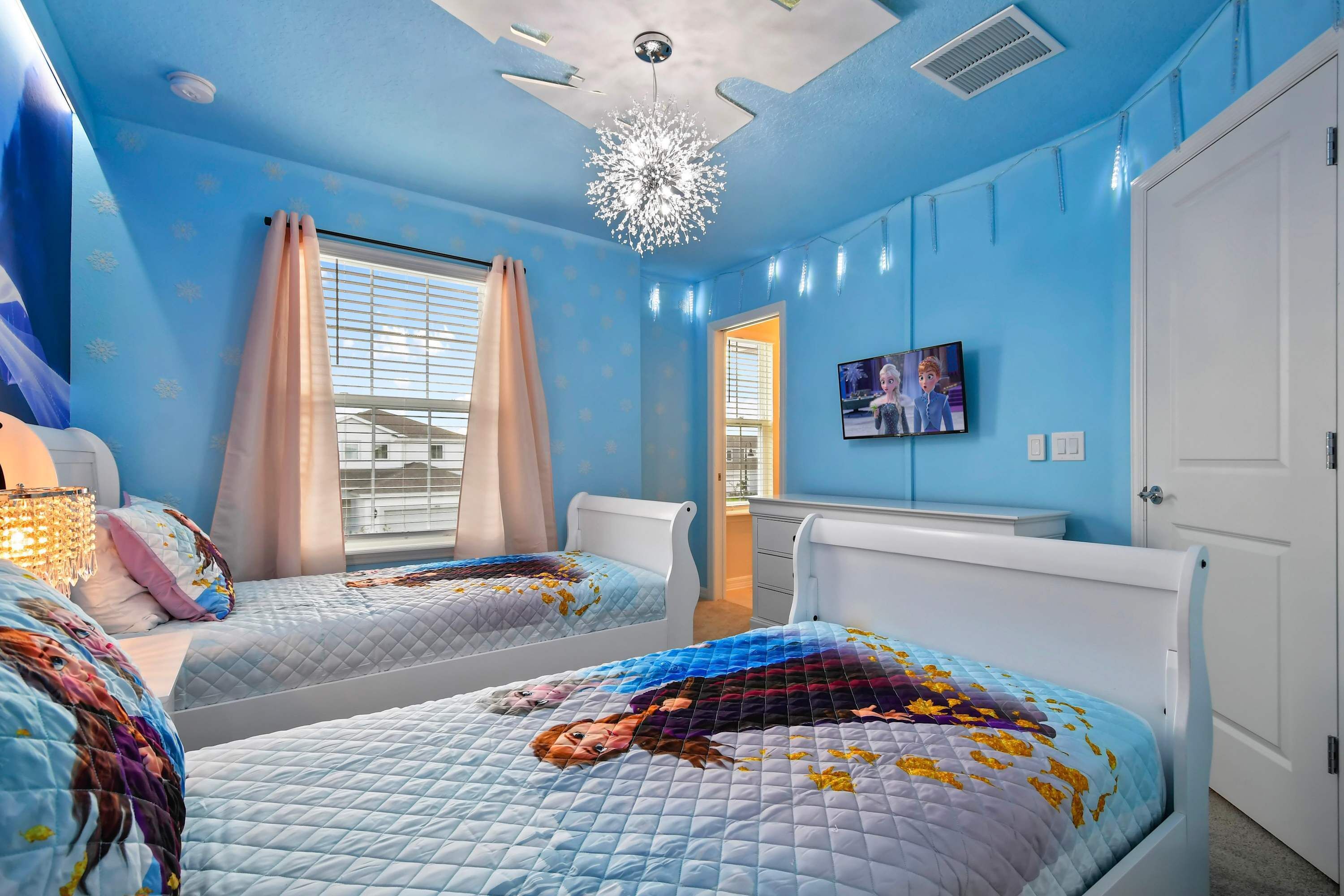 Un dormitorio con dos camas, un ventilador de techo y un televisor en la pared.