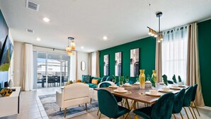 A modern dining area with a wooden table set for four, teal chairs, and a view of the dining area through glass doors. - Spacious Family Getaway at Windsor Island Resort (Davenport)