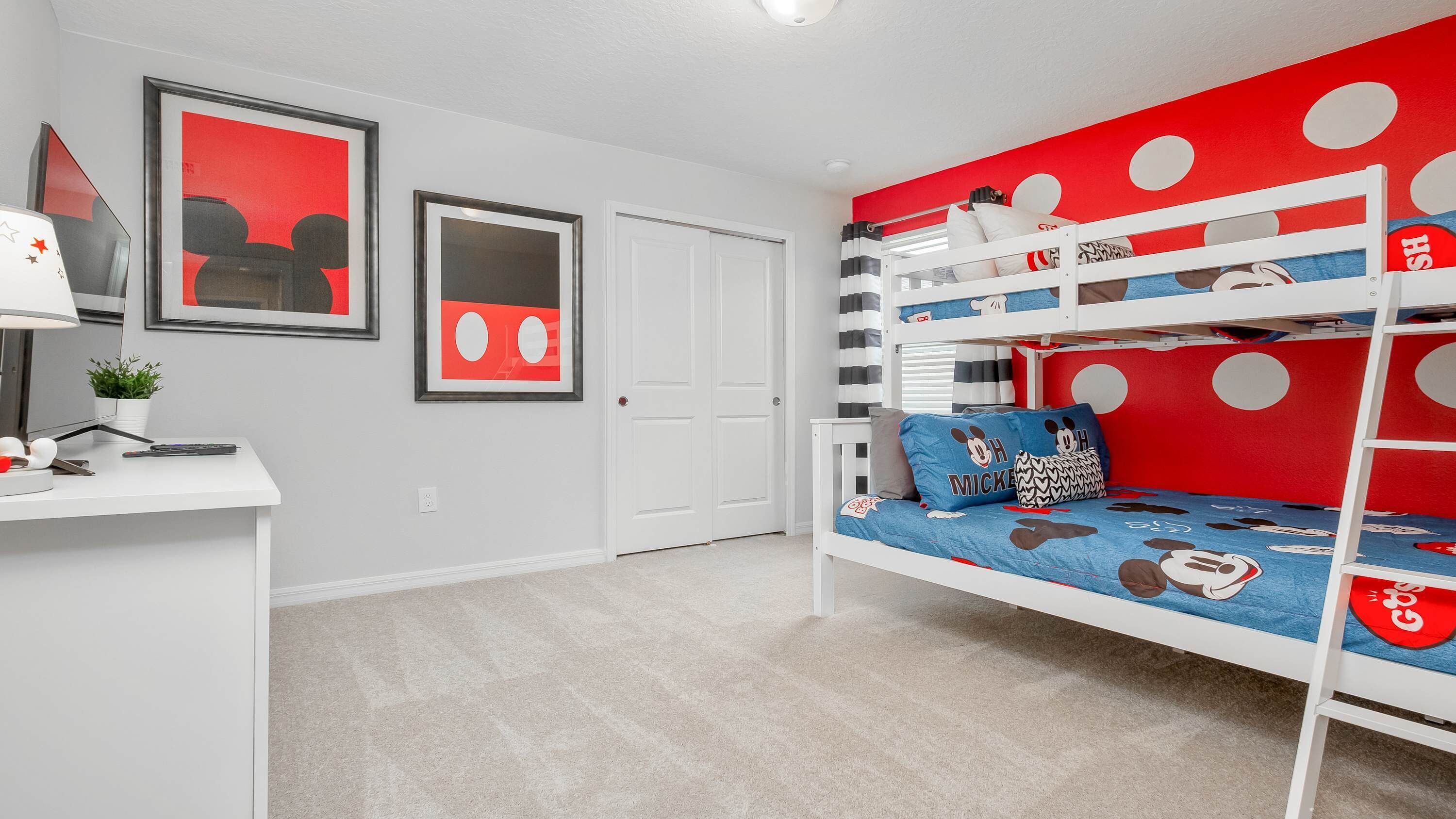 A child's bedroom with bunk beds, a desk, and two framed pictures on the wall.