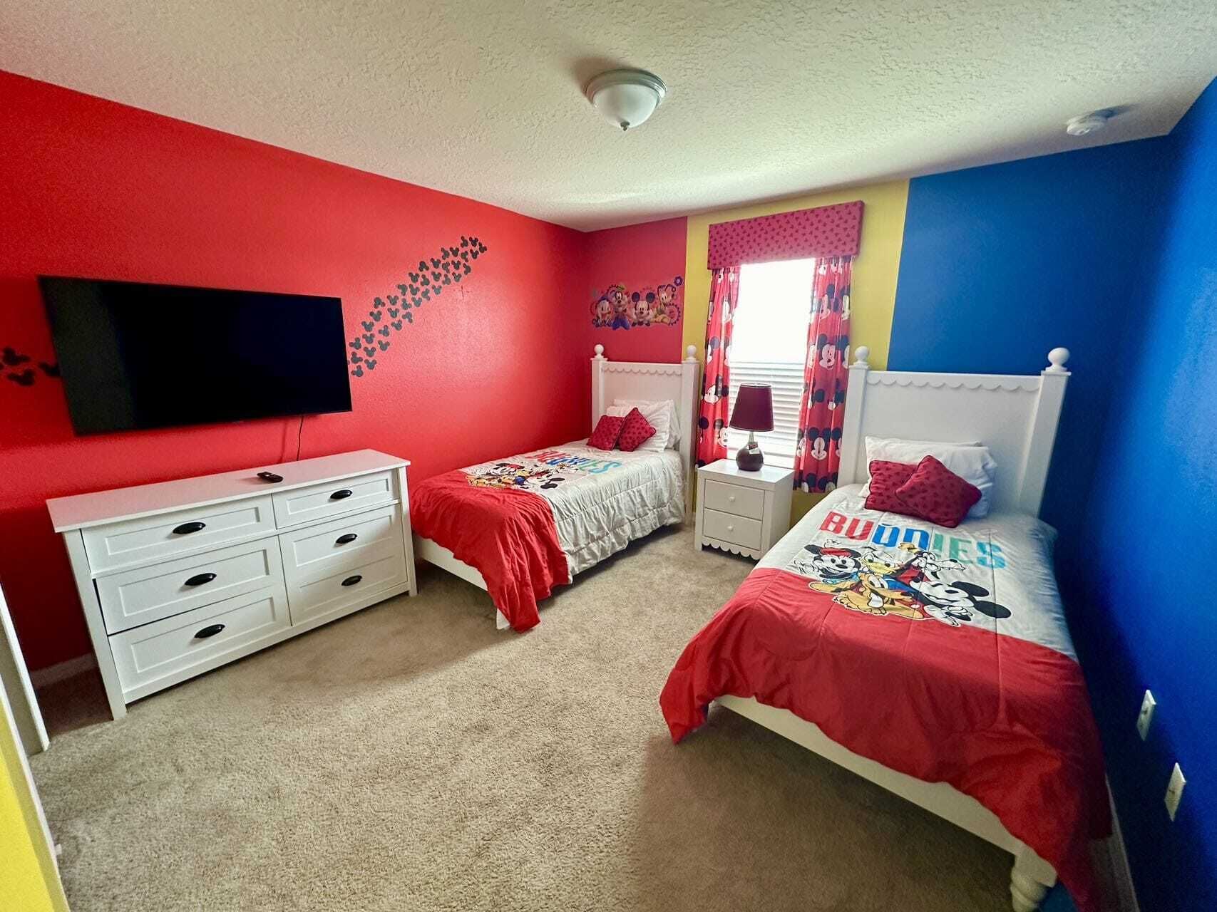 A bedroom with two beds, a TV, and a dresser.