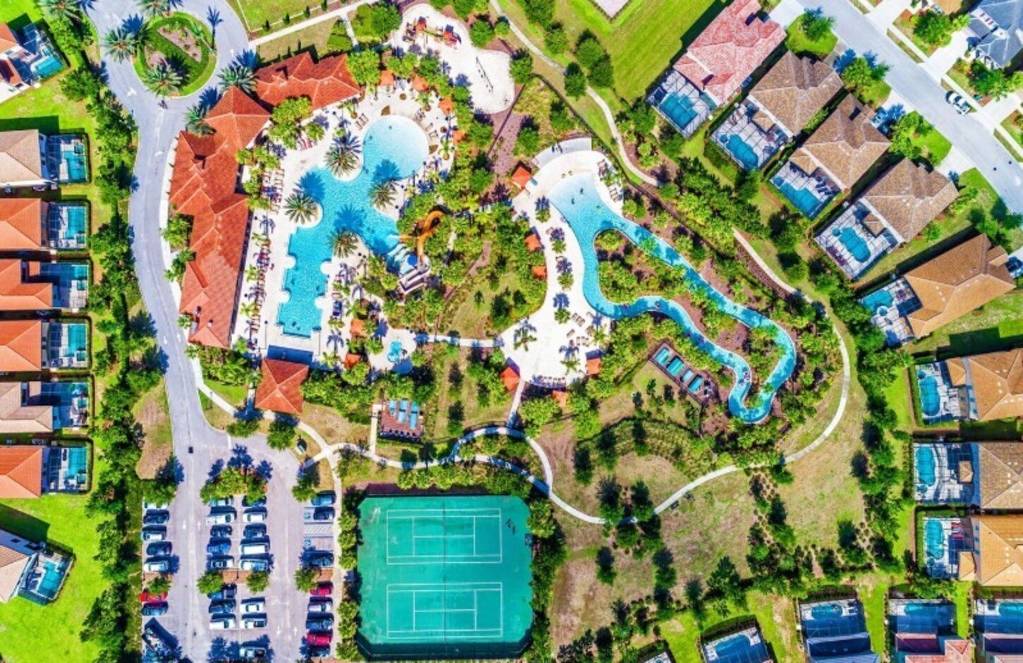 Vista aérea de un complejo turístico con varias piscinas, canchas de tenis y una variedad de edificios.