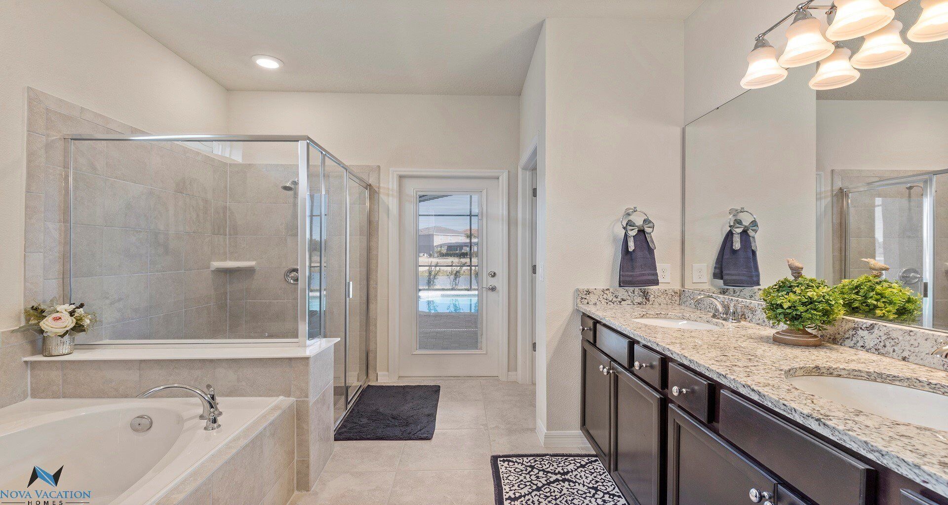 A modern bathroom with a glass-enclosed shower, a large mirror, and a granite countertop.