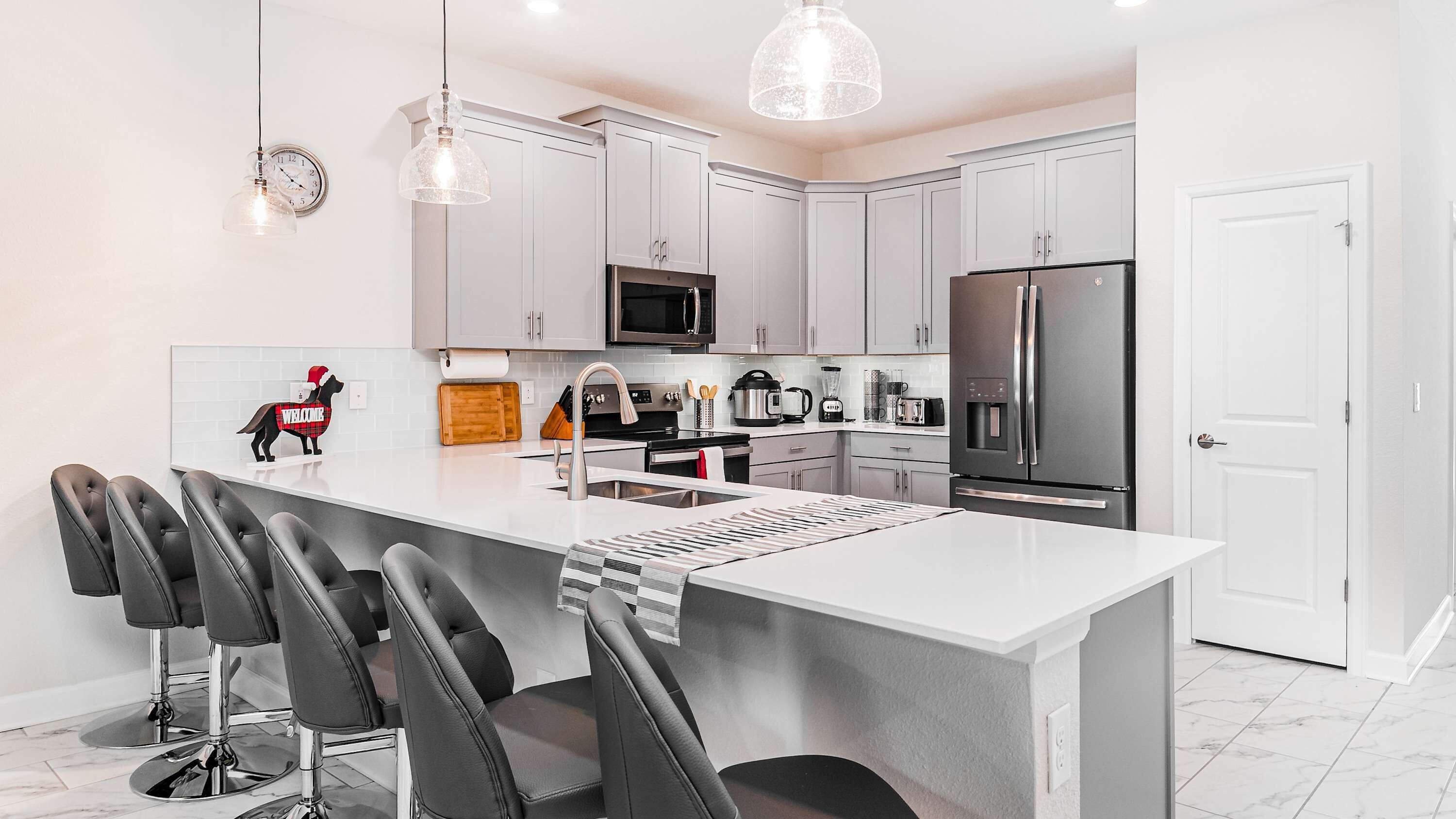 A modern kitchen with white cabinets, stainless steel appliances, and a central island with bar stools.