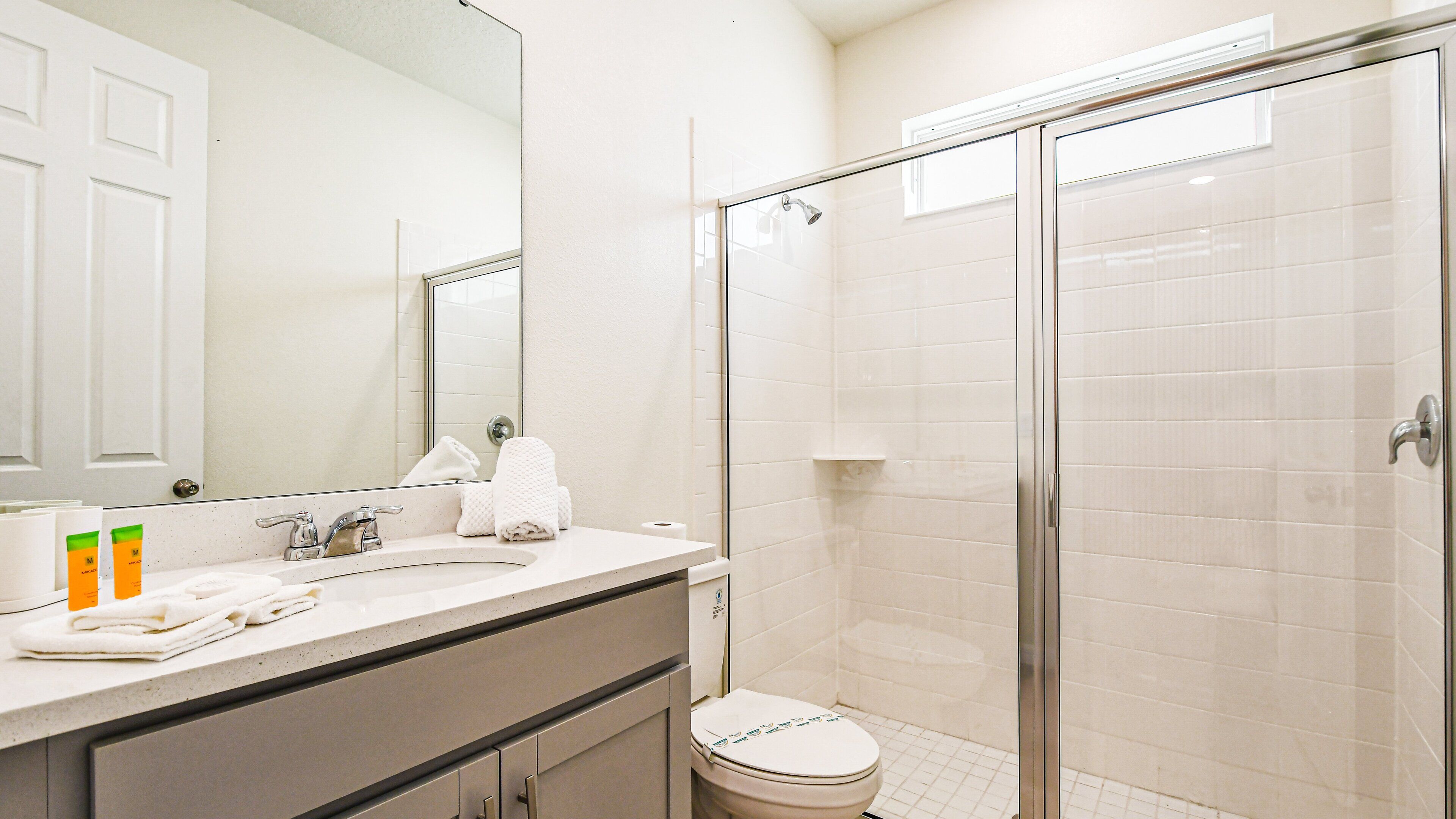 A bathroom with a sink, mirror, toilet, and shower.