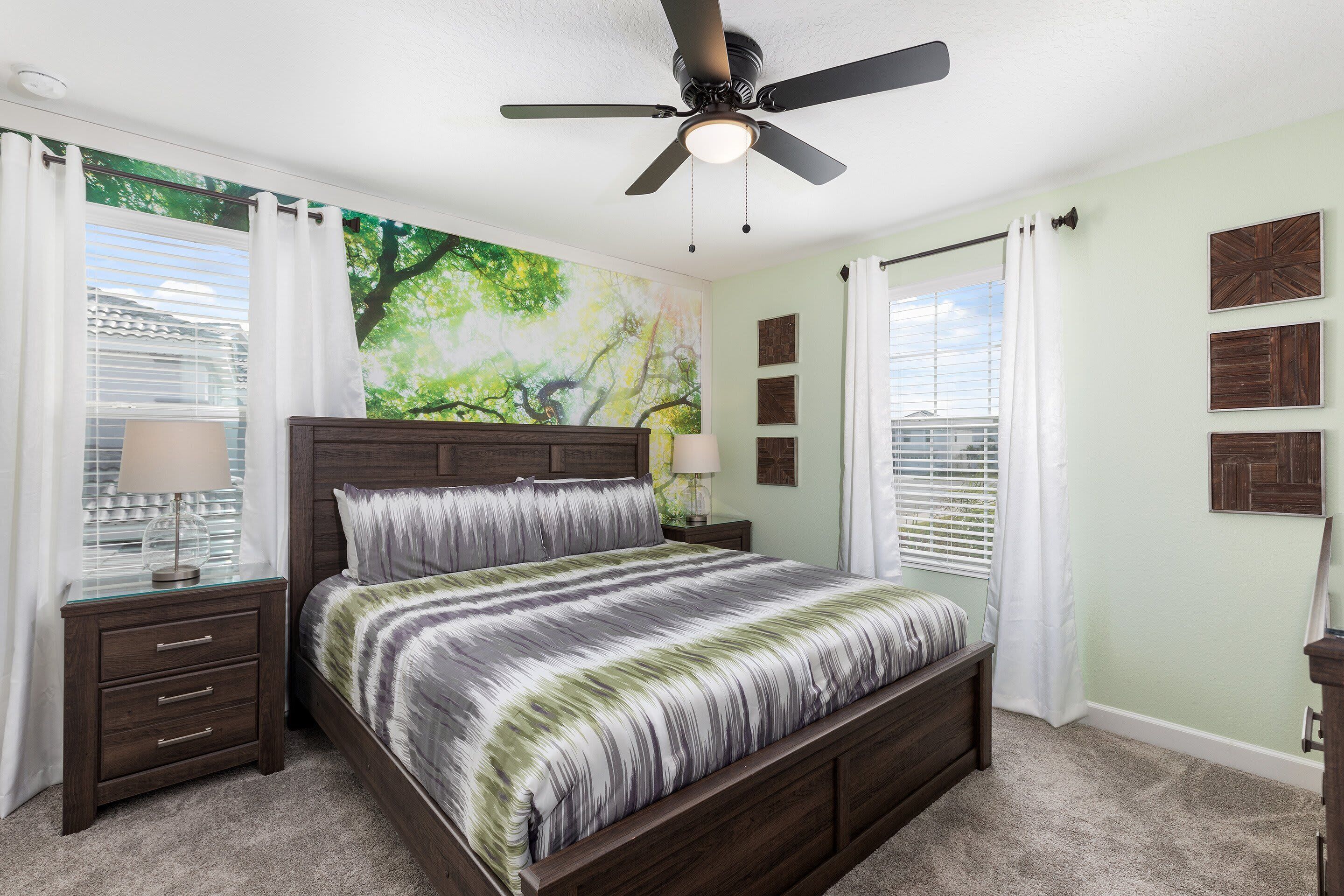 A bedroom with a bed, nightstands, a ceiling fan, and a window with curtains.