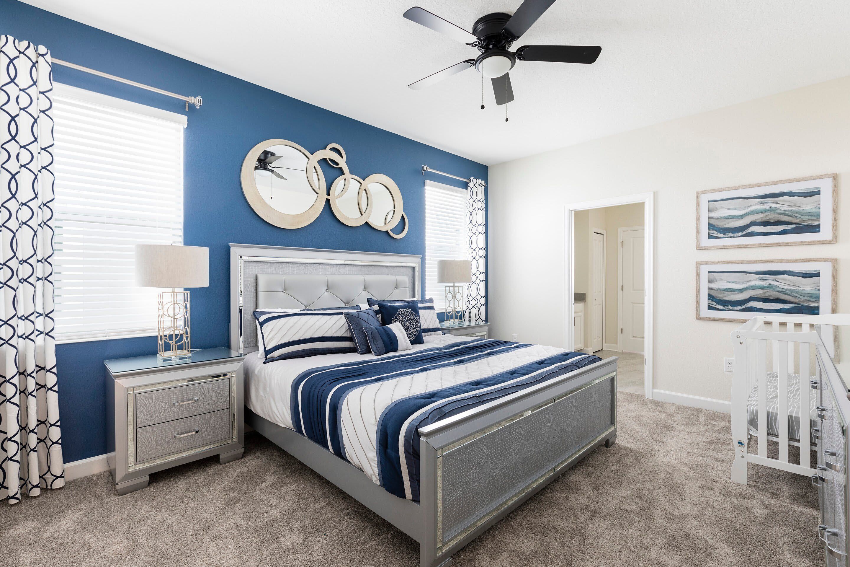 A bedroom with a bed, nightstands, a ceiling fan, and artwork on the walls.