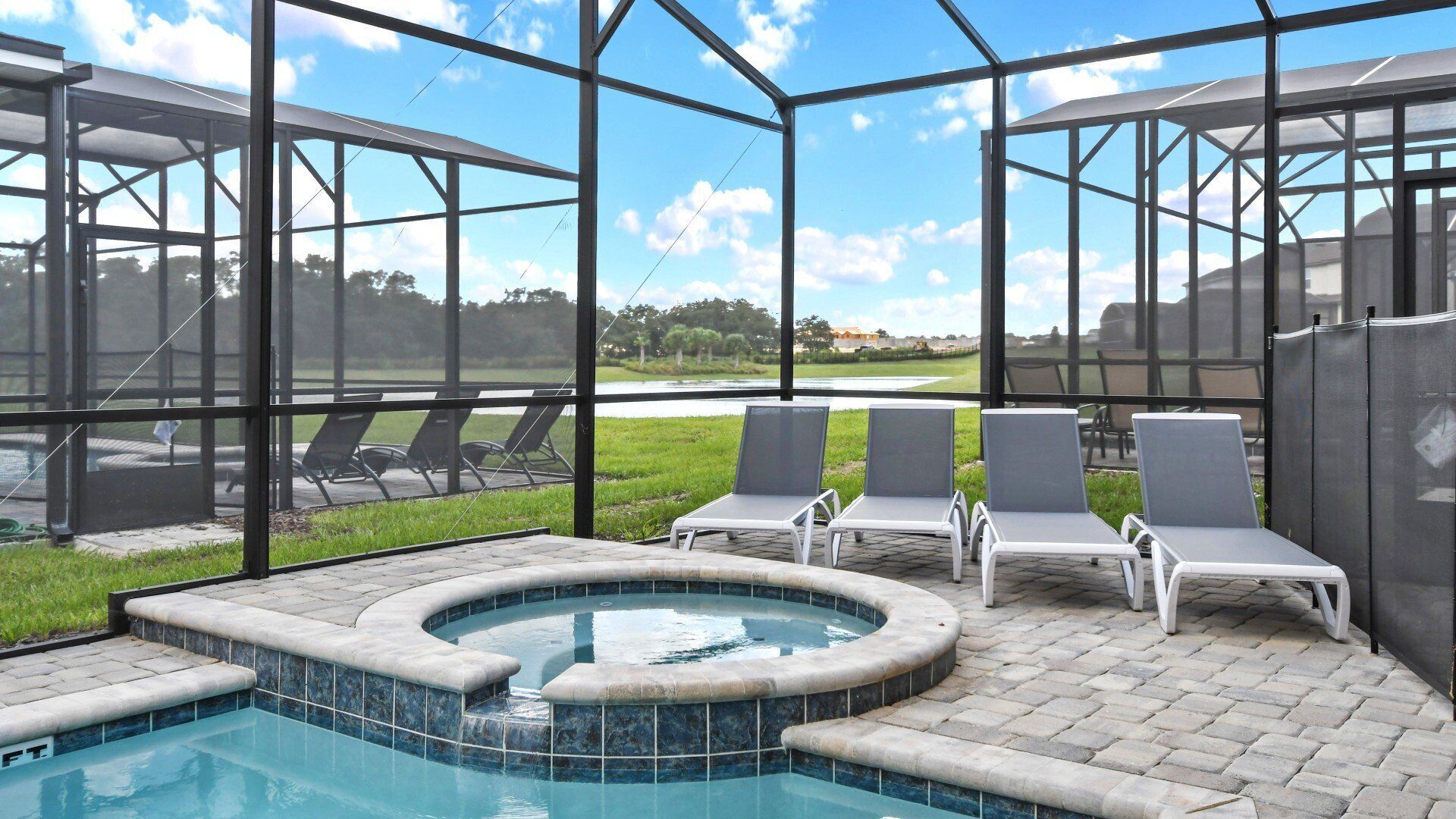 Un área de piscina con un jacuzzi, sillas de descanso y una estructura de vidrio con vistas al exterior.