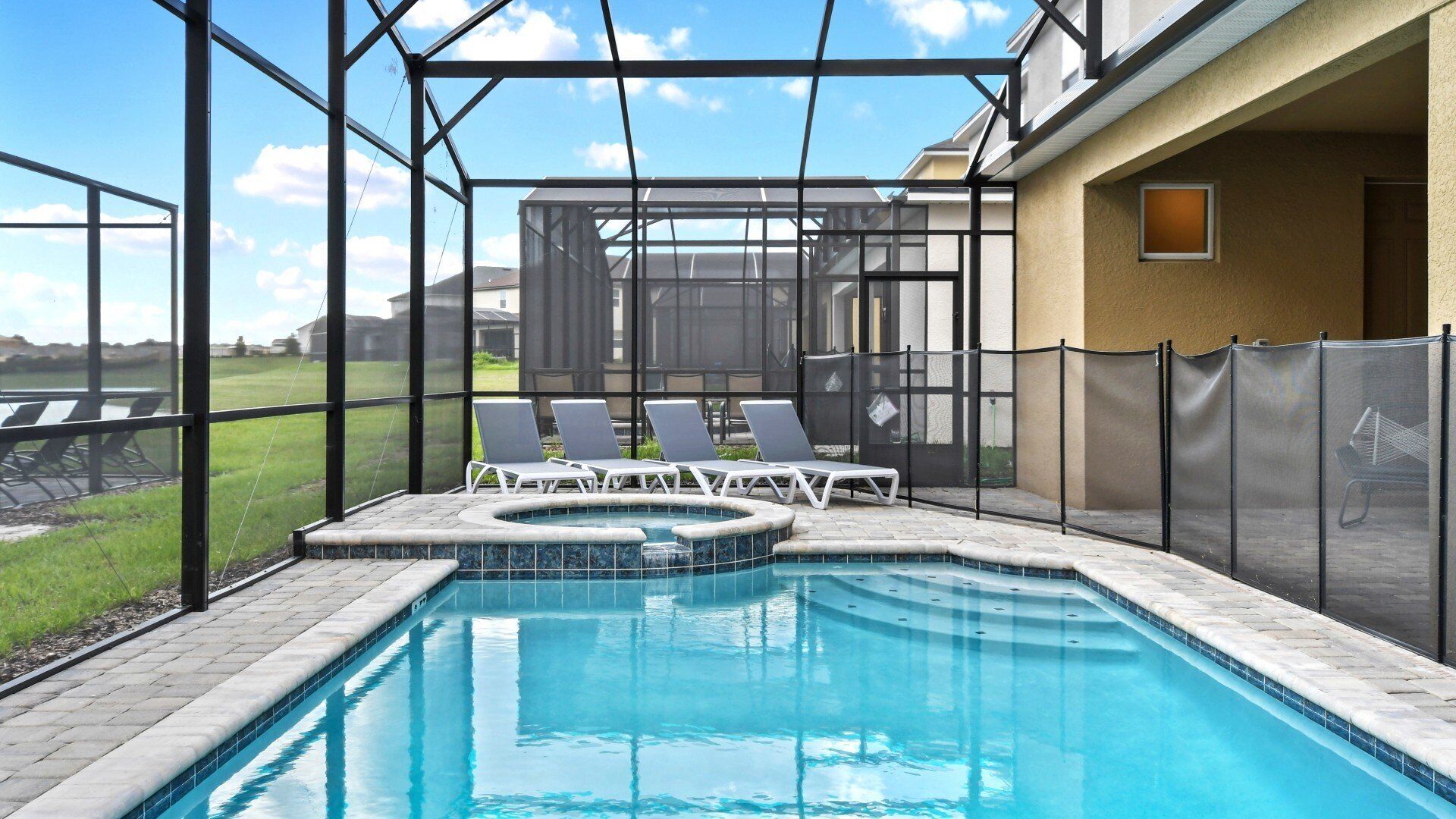 A swimming pool with a hot tub, surrounded by a covered area with lounge chairs.