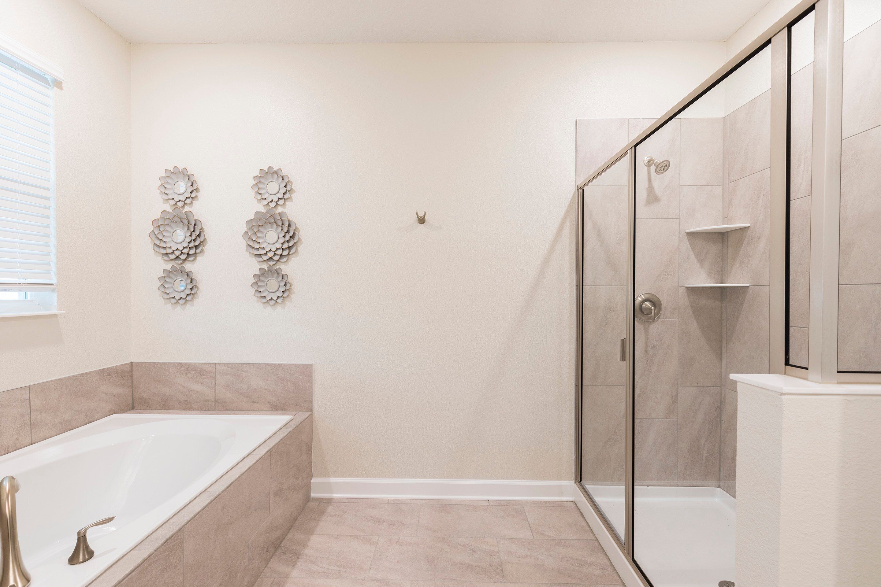 Un baño moderno con bañera, ducha y decoración mural.
