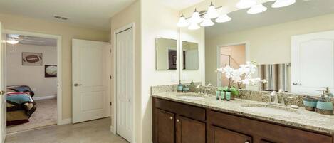 A bathroom with a double vanity, a large mirror, and a ceiling light fixture.