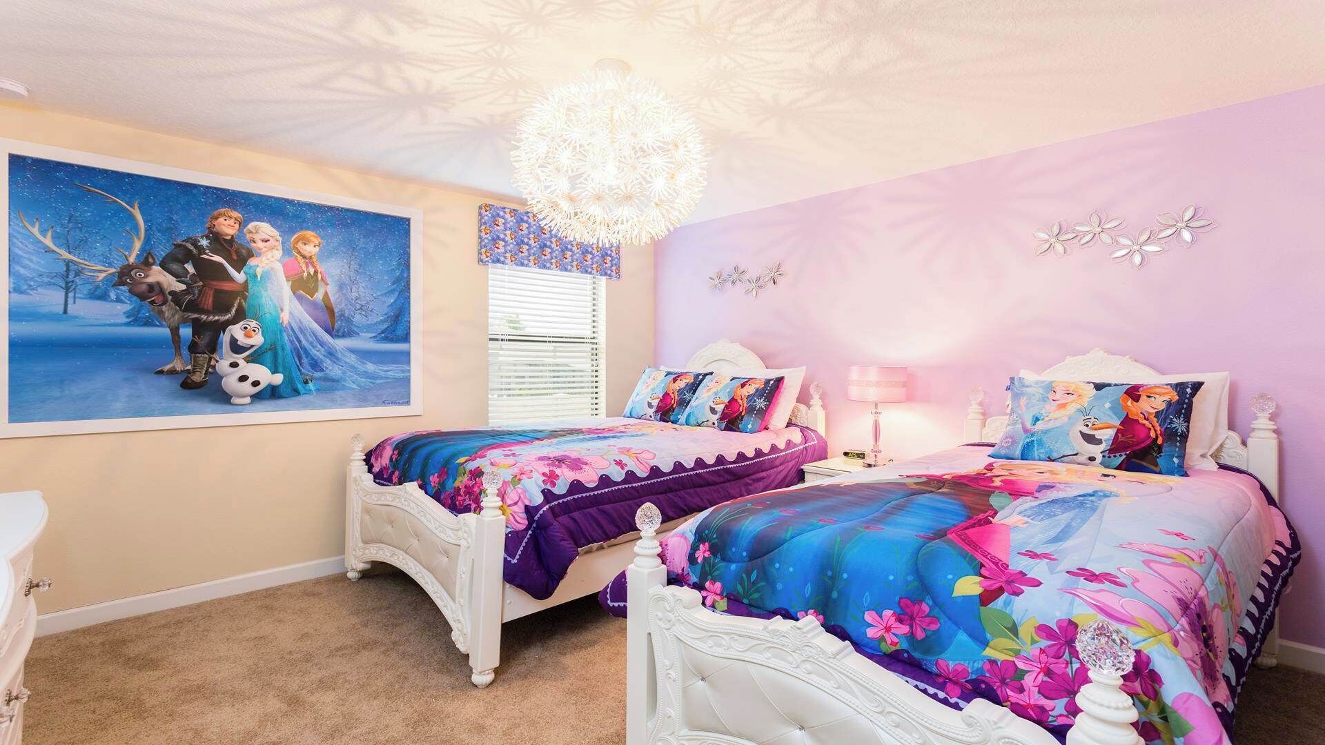 Une chambre à coucher avec deux lits blancs, une literie à motifs floraux, une grande affiche de personnages de dessins animés et un lustre.