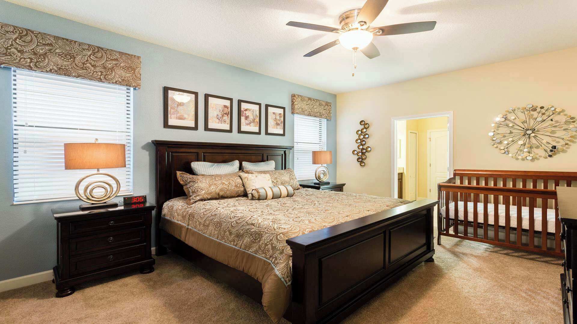 Ein Schlafzimmer mit Bett, Nachttischen, Deckenventilator und Wanduhr.