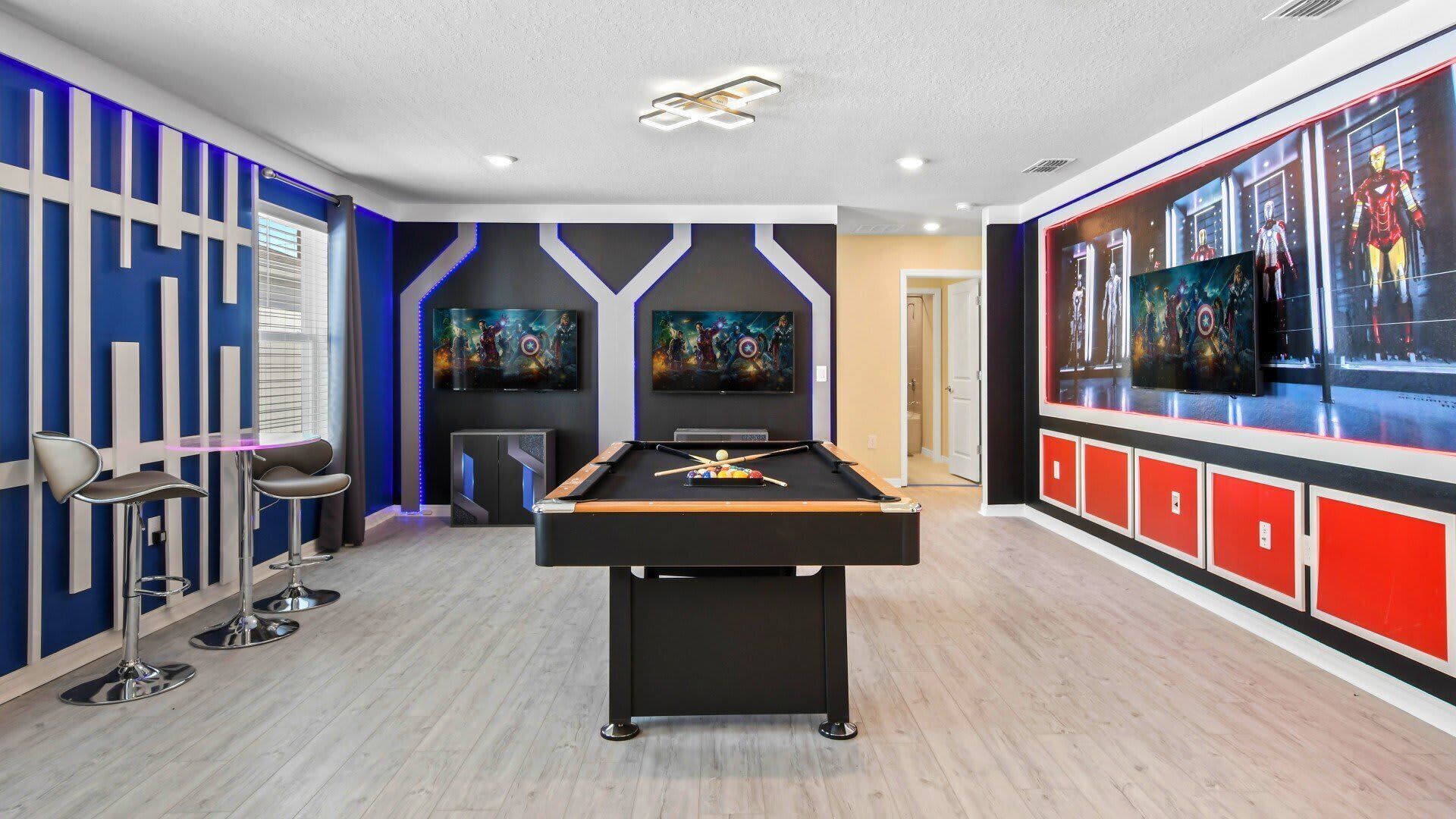 A pool table in a room with a modern design, including a large TV screen displaying a movie, a pool table, and a bar area with stools.