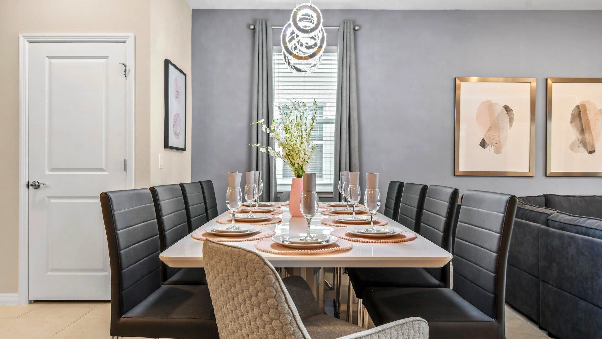 A dining room with a rectangular table set for six, surrounded by black leather booths.