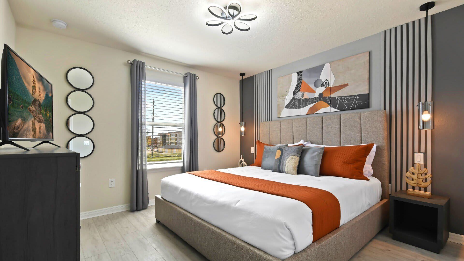 Un dormitorio moderno con una cama grande, televisión de pantalla plana y vistas a la ciudad.