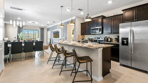 Una cocina moderna con armarios de madera oscura, electrodomésticos de acero inoxidable y una isla central con taburetes de bar.