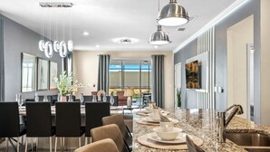 Una cocina moderna con encimeras de granito, electrodomésticos de acero inoxidable e iluminación colgante.